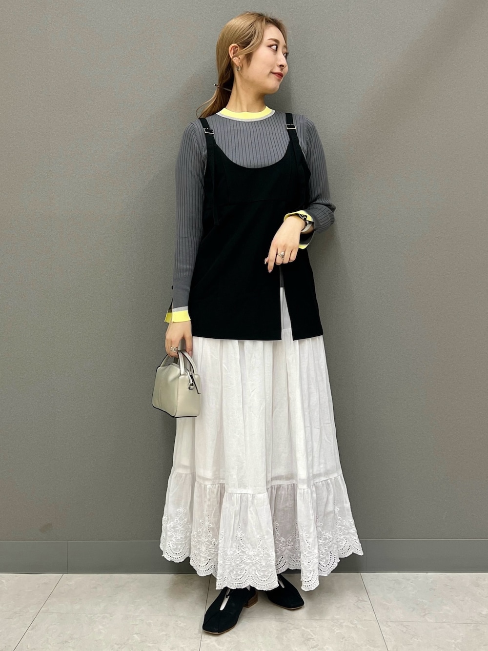 ブラック系のその他トップス、グレー系のニット/セーター、ホワイト系のスカートを着用したレディースの春コーディネートの1枚目の写真