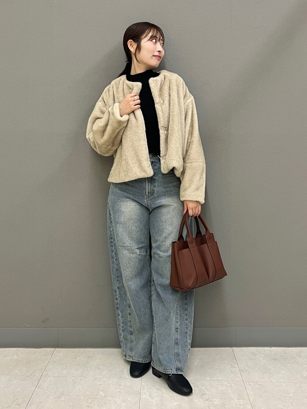 ベージュ系のブルゾン、ブラック系のニット/セーター、ブルー系のデニムパンツを着用したレディースの秋コーディネートの1枚目の写真