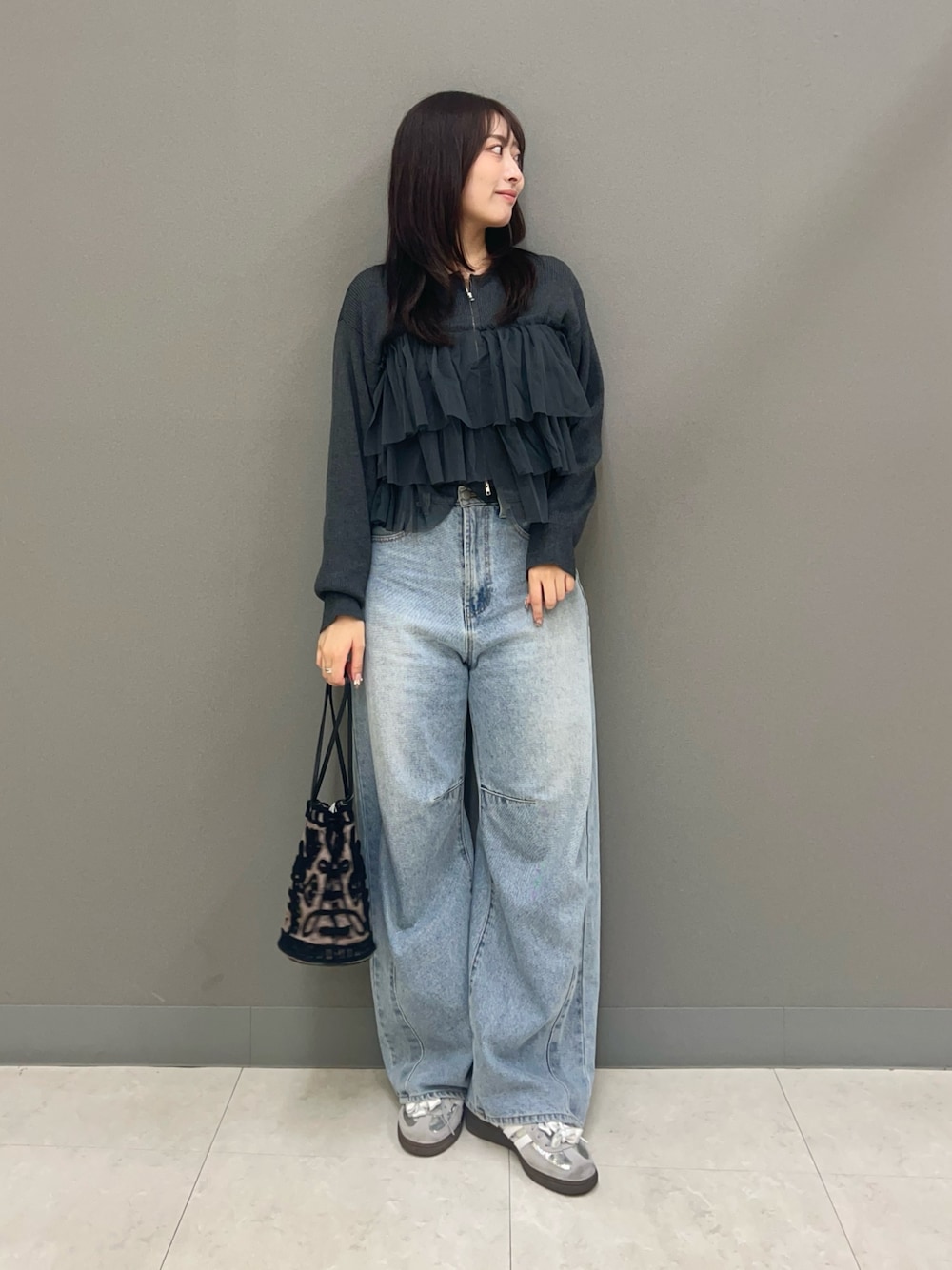 ブルー系のデニムパンツ、ブラウン系のハンドバッグ、グレー系のニット/セーターを着用したレディースの秋コーディネートの1枚目の写真
