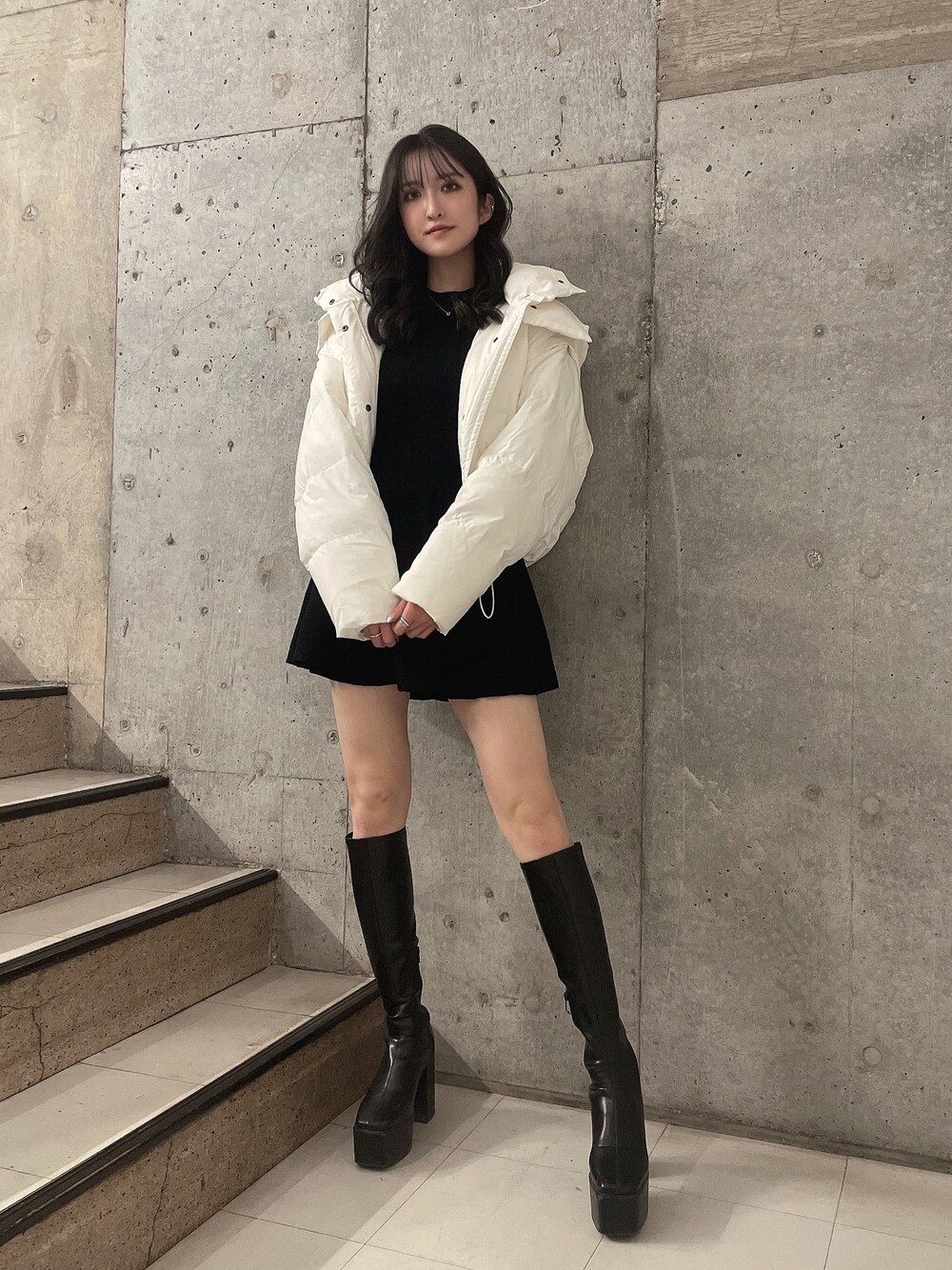 ホワイト系のダウンジャケット/コート、ブラック系のワンピース、ブラック系のブーツを着用したレディースの冬コーディネートの1枚目の写真