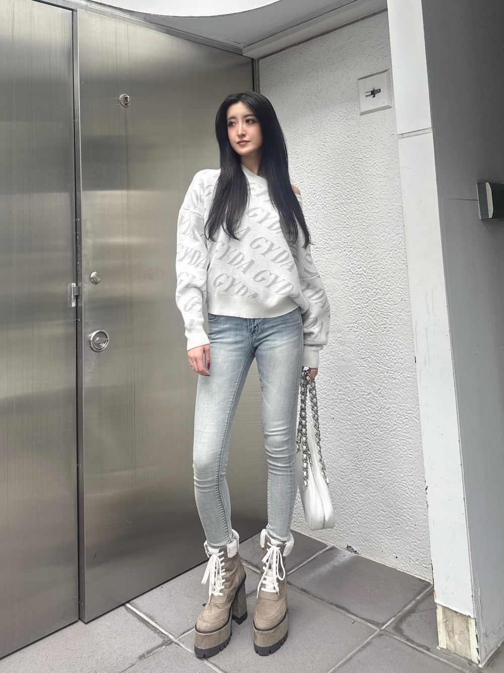 ホワイト系のニット/セーター、ホワイト系のショルダーバッグ、ブルー系のデニムパンツを着用したレディースの秋コーディネートの1枚目の写真