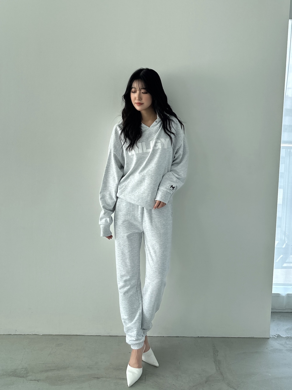 グレー系のパーカー、グレー系のスウェットパンツ、ホワイト系のパンプスを着用したレディースの秋コーディネートの1枚目の写真