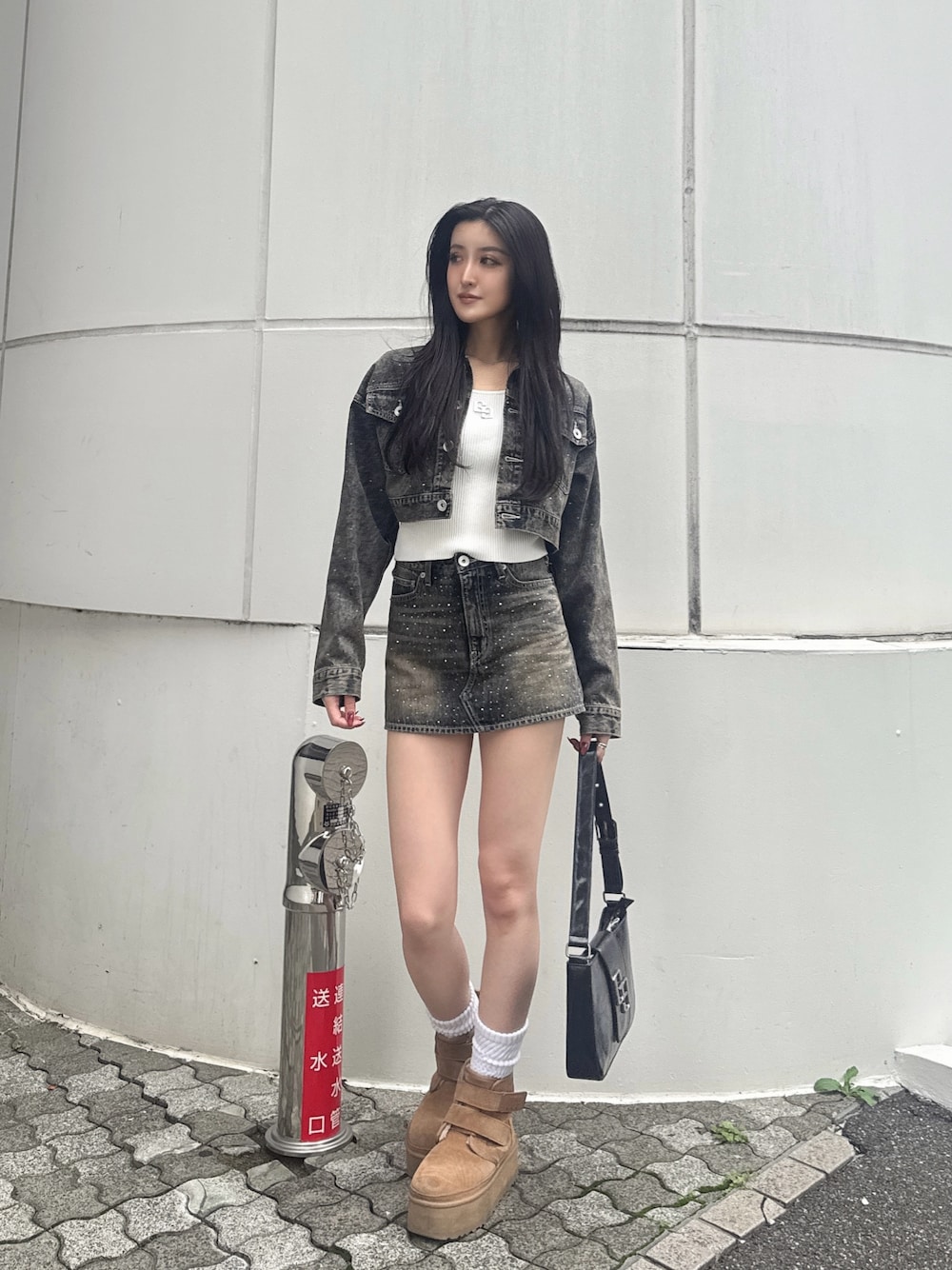 ブラック系のハンドバッグ、ブルー系のデニムジャケット、ブルー系のデニムスカートを着用したレディースの秋コーディネートの1枚目の写真