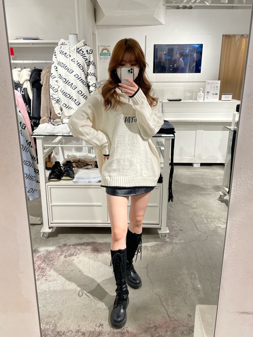 ホワイト系のニット/セーター、ブラック系のスカート、ブラック系のブーツを着用したレディースの冬コーディネートの1枚目の写真