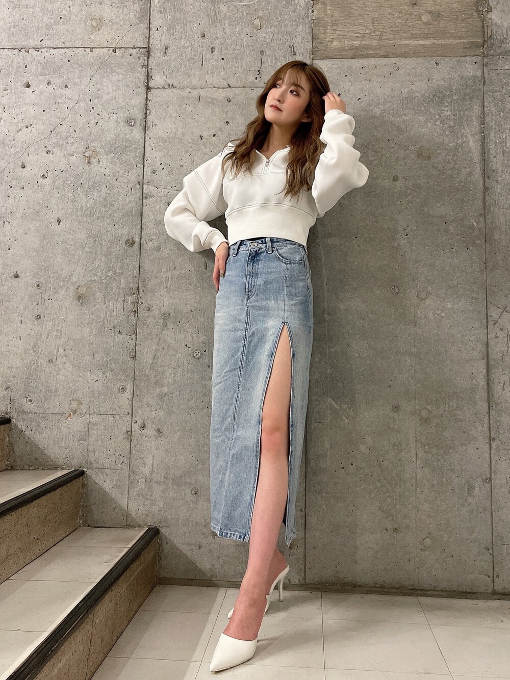 ホワイト系のパーカー、ブルー系のデニムスカート、ホワイト系のパンプスを着用したレディースの冬コーディネートの1枚目の写真