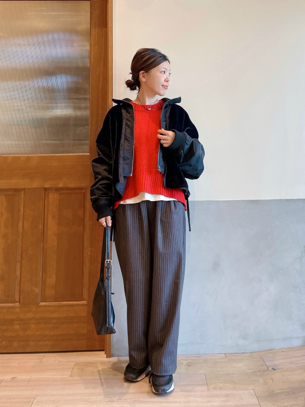 レッド系のニット/セーター、ブラック系のブルゾン、グレー系のスラックスを着用したレディースの冬コーディネートの1枚目の写真