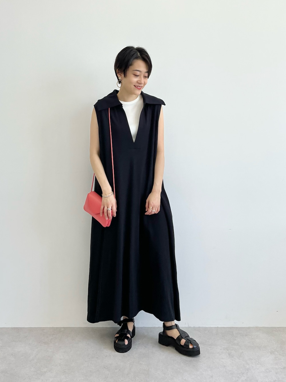 ブラック系のワンピース、ピンク系のショルダーバッグ、ブラック系のサンダルを着用したレディースの春コーディネートの1枚目の写真