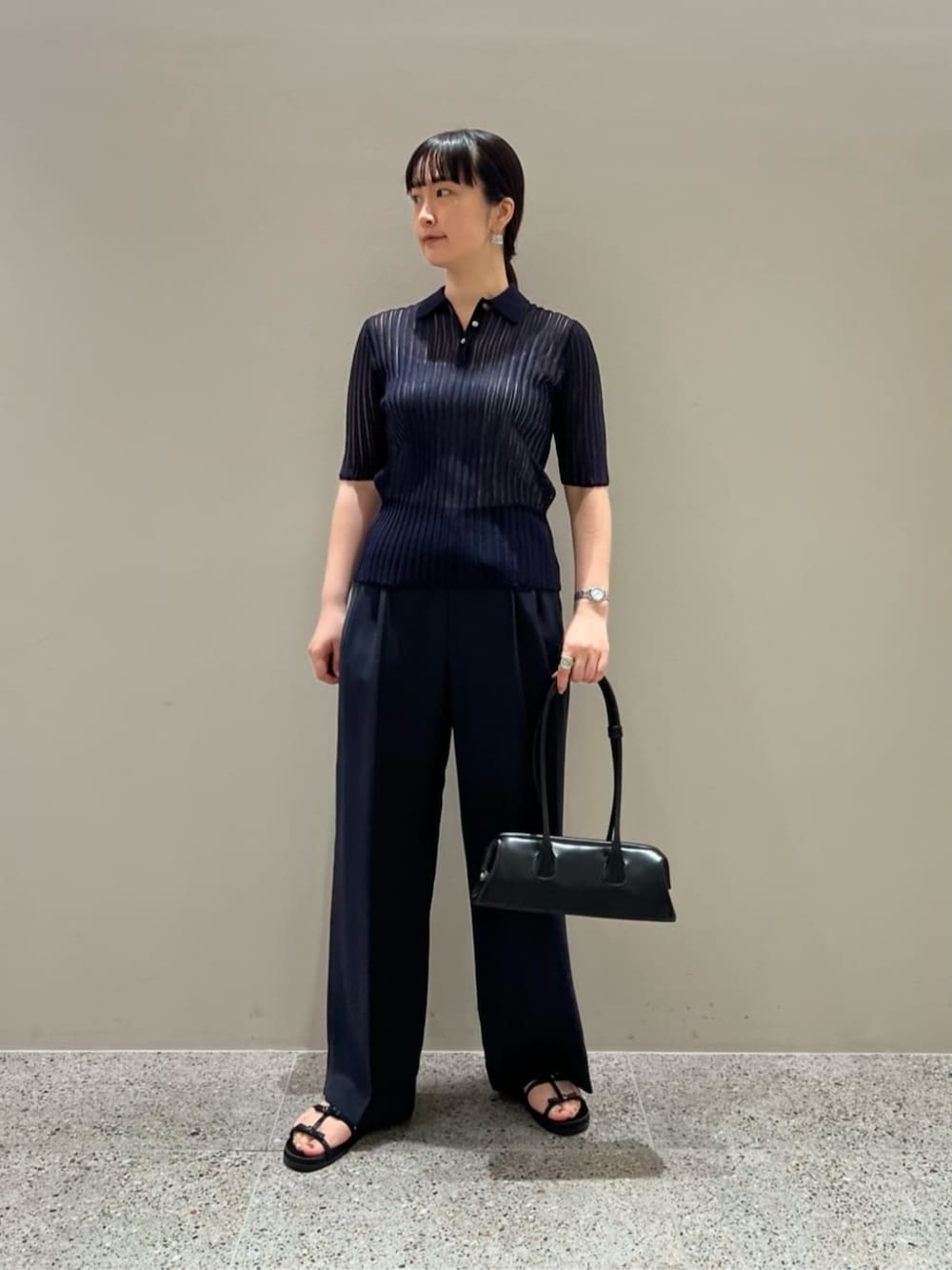 ブラック系のショルダーバッグ、ブルー系のニット/セーター、ブルー系のスラックスを着用したレディースの夏コーディネートの1枚目の写真