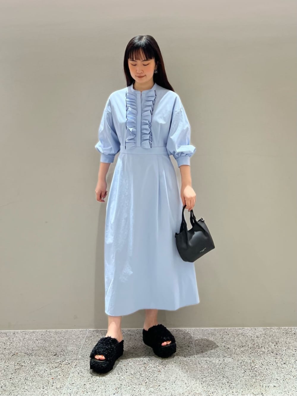 ブルー系のワンピース、ブラック系のハンドバッグを着用したレディースの春コーディネートの1枚目の写真