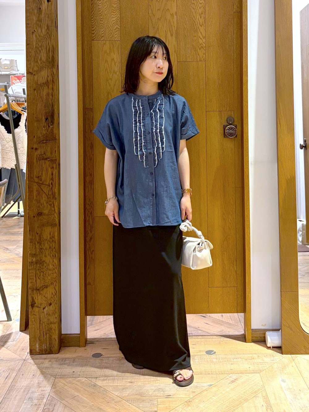 ブラック系のスカート、ベージュ系のショルダーバッグ、ブラウン系のサンダルを着用したレディースの夏コーディネートの1枚目の写真
