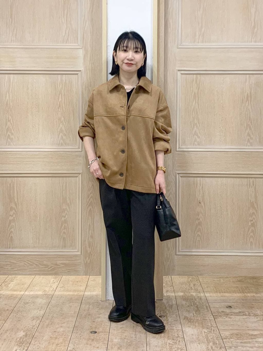 ブラック系のショルダーバッグ、ブラック系のブーツ、ブラウン系のテーラードジャケットを着用したレディースの春コーディネートの1枚目の写真
