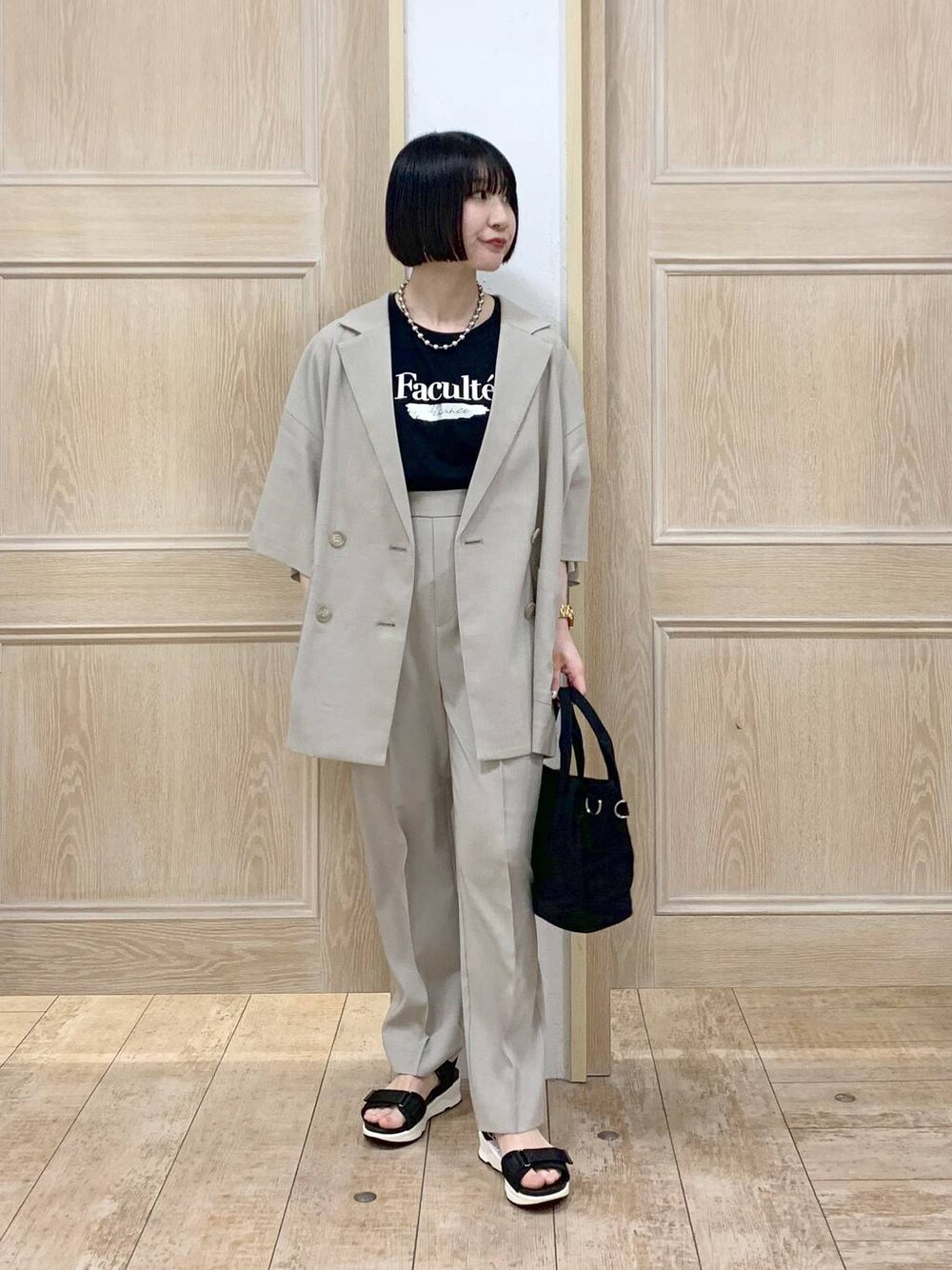 ブラック系のTシャツ/カットソー、ブラック系のトートバッグ、ベージュ系のテーラードジャケットを着用したレディースの春コーディネートの1枚目の写真