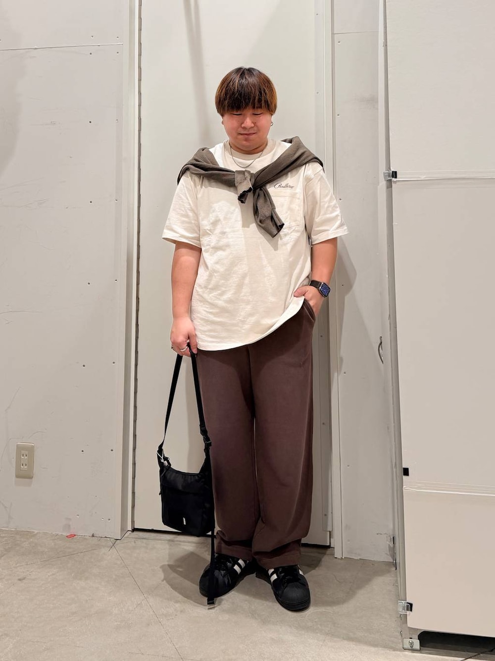 ブラック系のその他シューズ、ホワイト系のTシャツ/カットソー、ブラック系のショルダーバッグを着用したメンズの春コーディネートの1枚目の写真