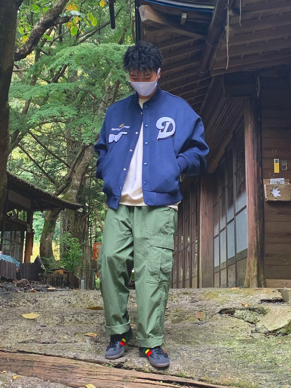 ブルー系のスタジャン、ホワイト系のスウェット、グリーン系のカーゴパンツを着用したメンズの秋コーディネートの1枚目の写真