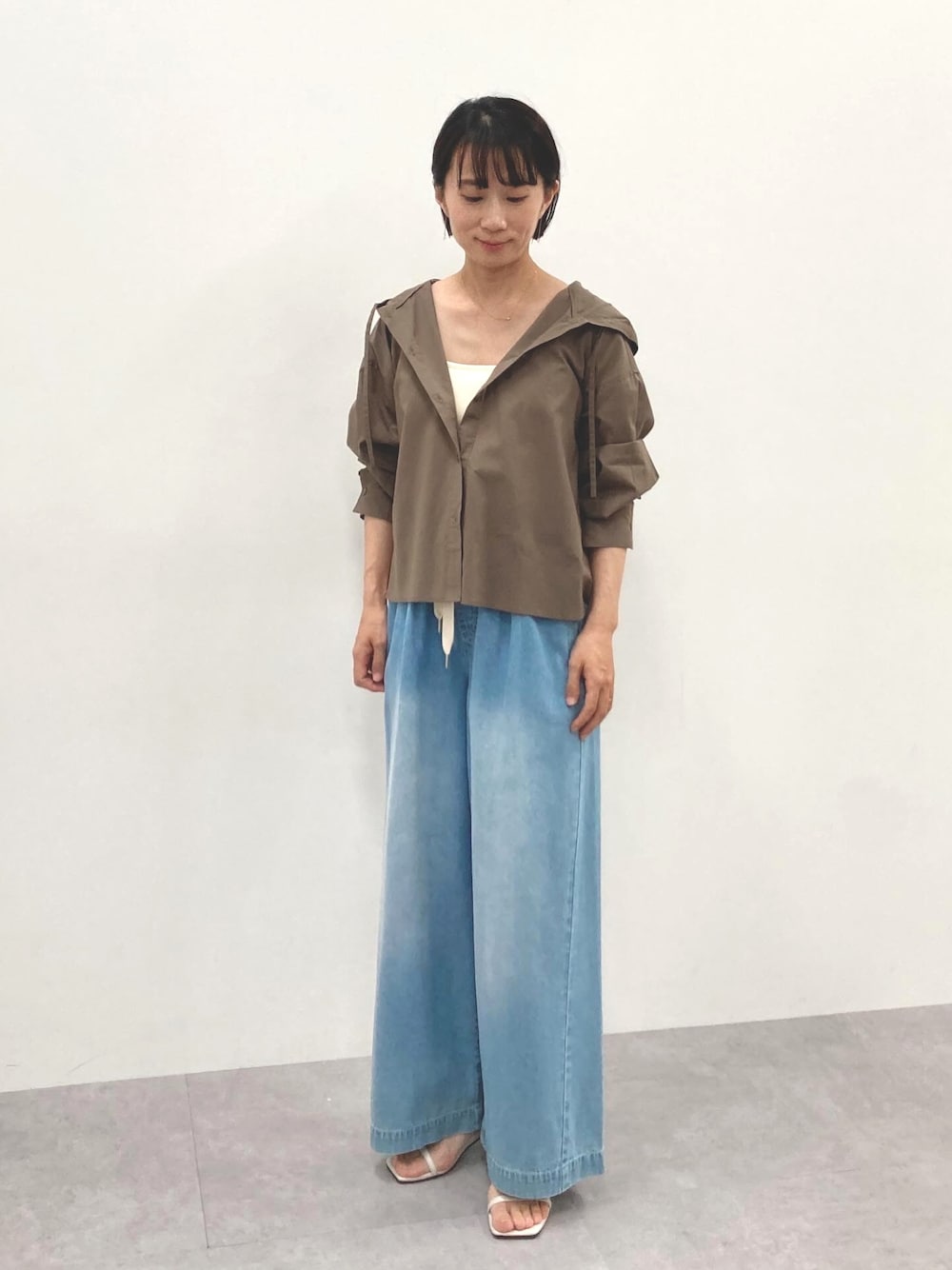 ブラウン系のシャツ/ブラウス、ブルー系のパンツを着用したレディースの春コーディネートの1枚目の写真