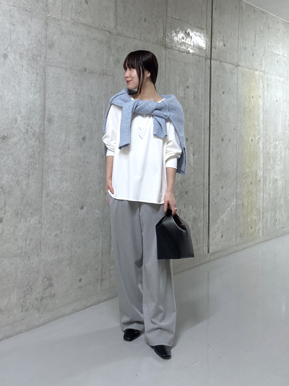 ブルー系のニット/セーター、ホワイト系のTシャツ/カットソー、ブラック系のハンドバッグを着用したレディースの秋コーディネートの1枚目の写真