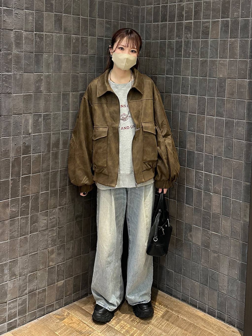 ブルー系のデニムパンツ、ブラウン系のブルゾン、ブラック系のローファーを着用したレディースの秋コーディネートの1枚目の写真