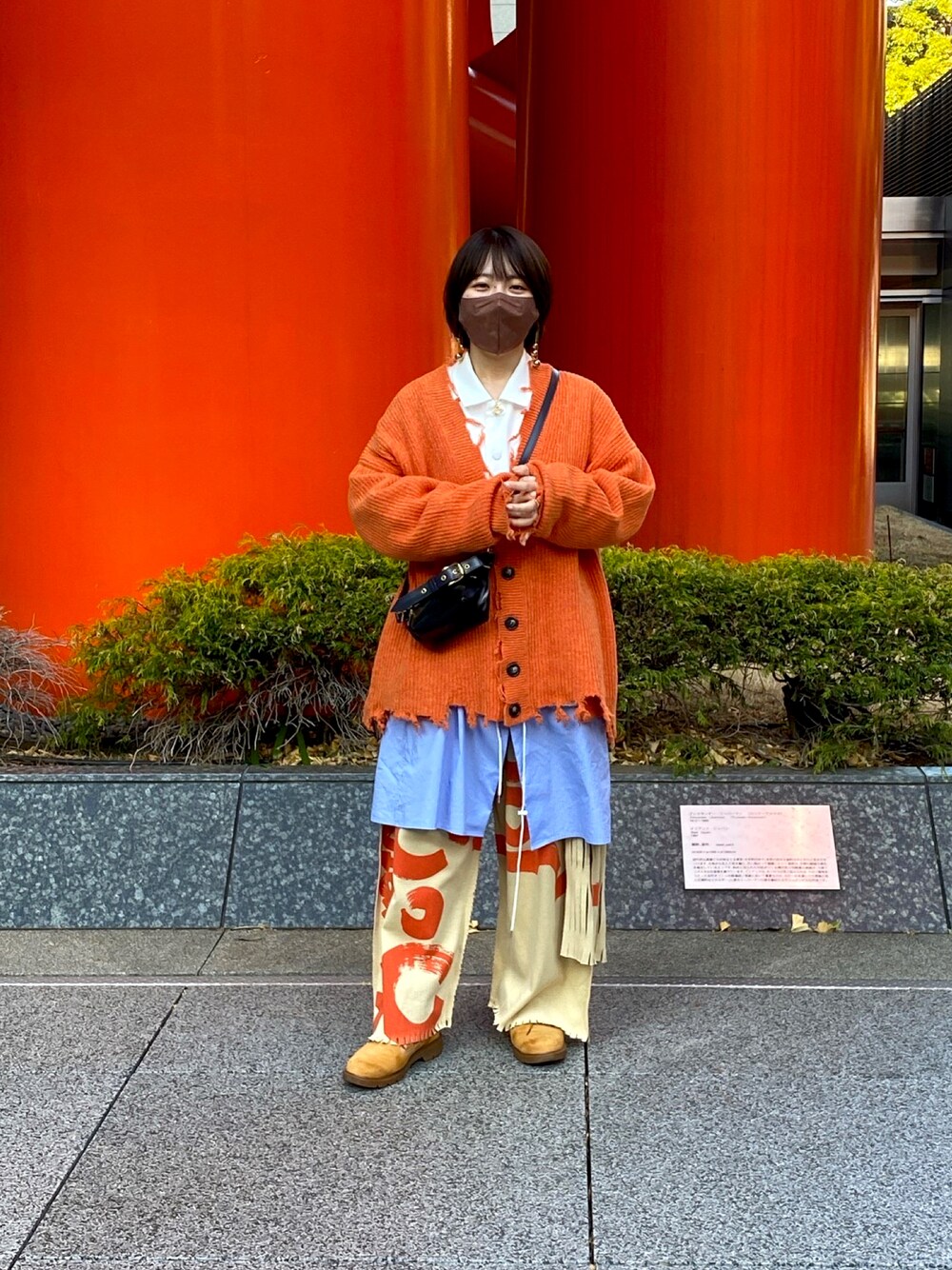 オレンジ系のカーディガン/ボレロ、ブラック系のショルダーバッグ、ホワイト系のシャツ/ブラウスを着用したレディースの冬コーディネートの1枚目の写真