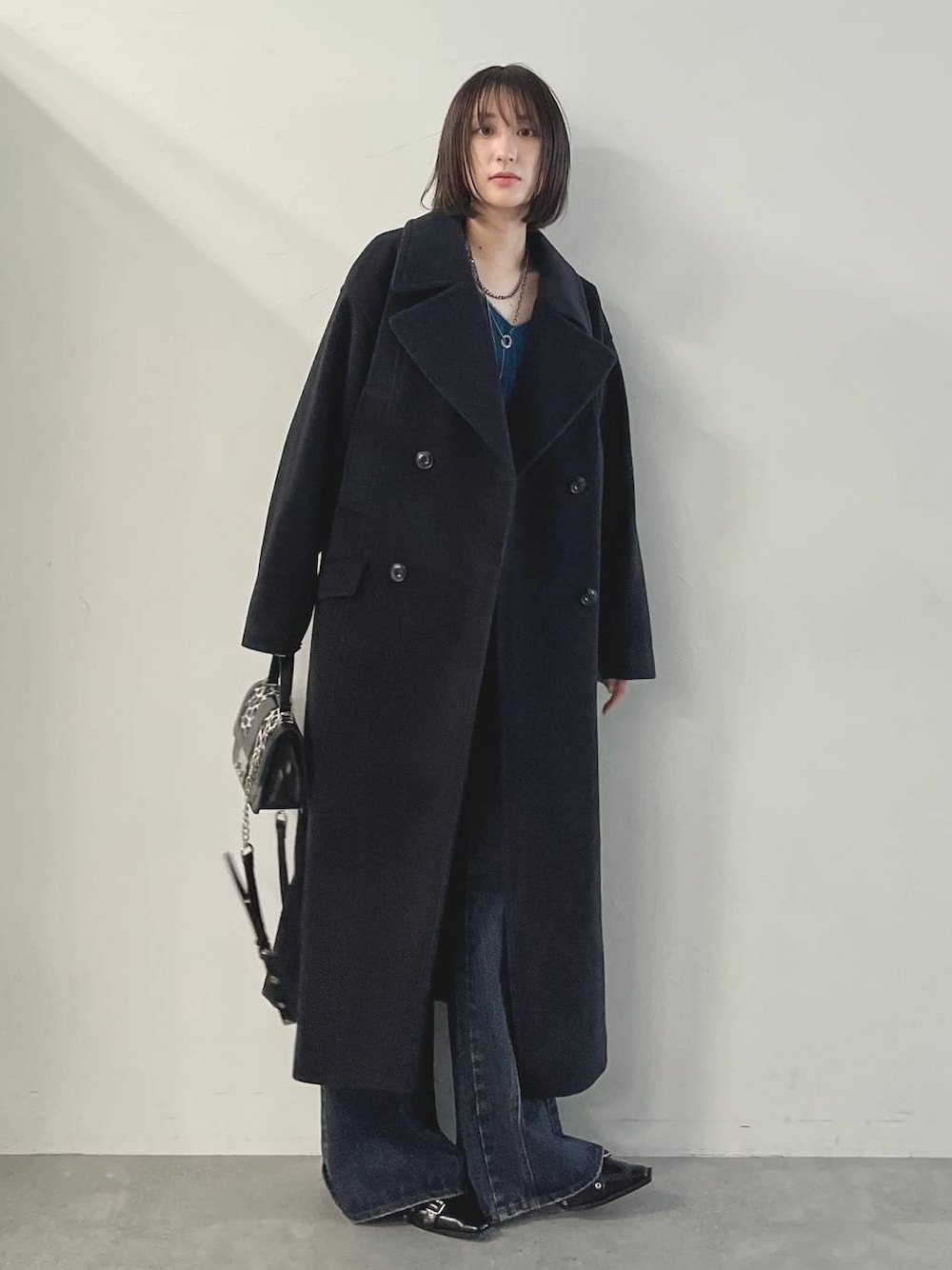 ブルー系のデニムパンツ、ブラック系のパンプス、ブラック系のチェスターコートを着用したレディースの秋コーディネートの1枚目の写真