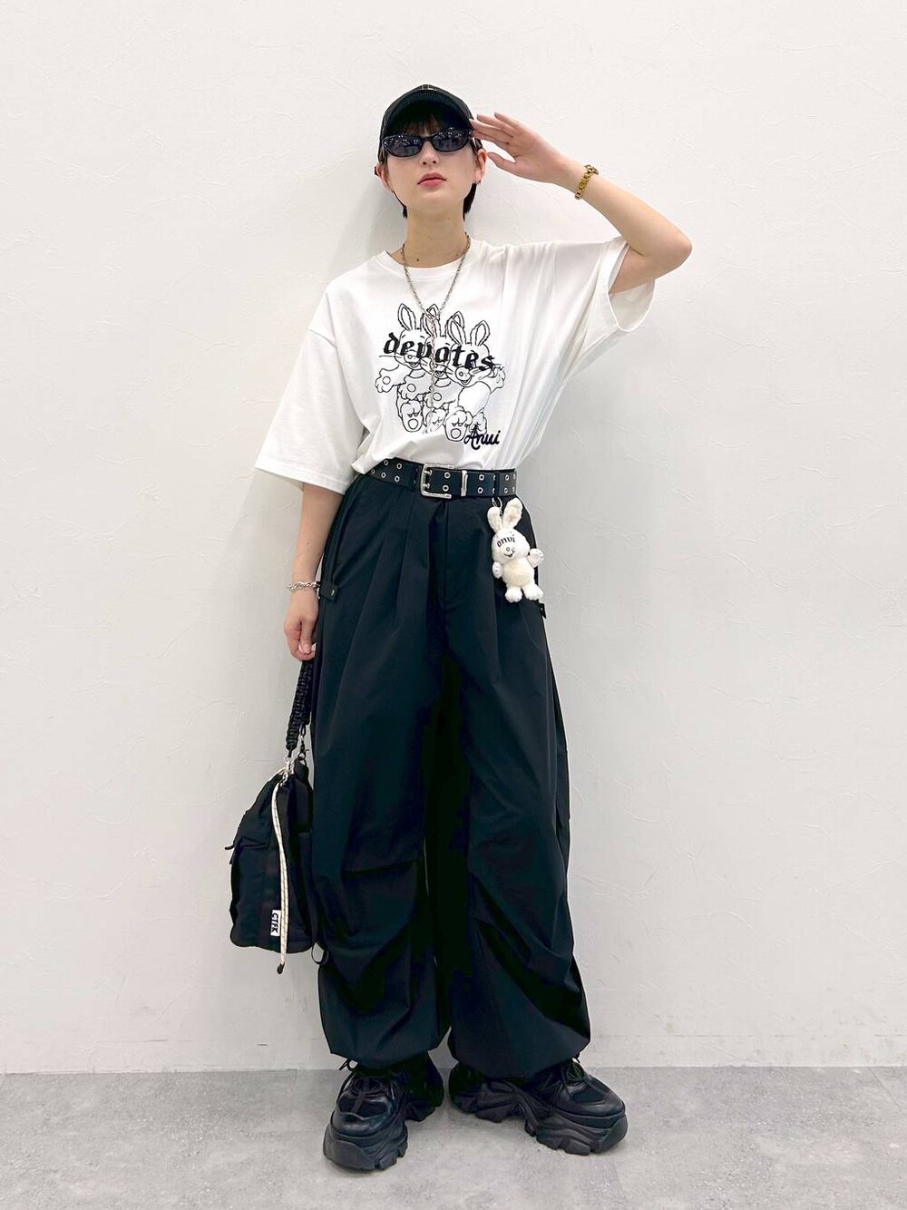 ブラック系のスニーカー、ホワイト系のTシャツ/カットソー、ブラック系のショルダーバッグを着用したレディースの夏コーディネートの1枚目の写真