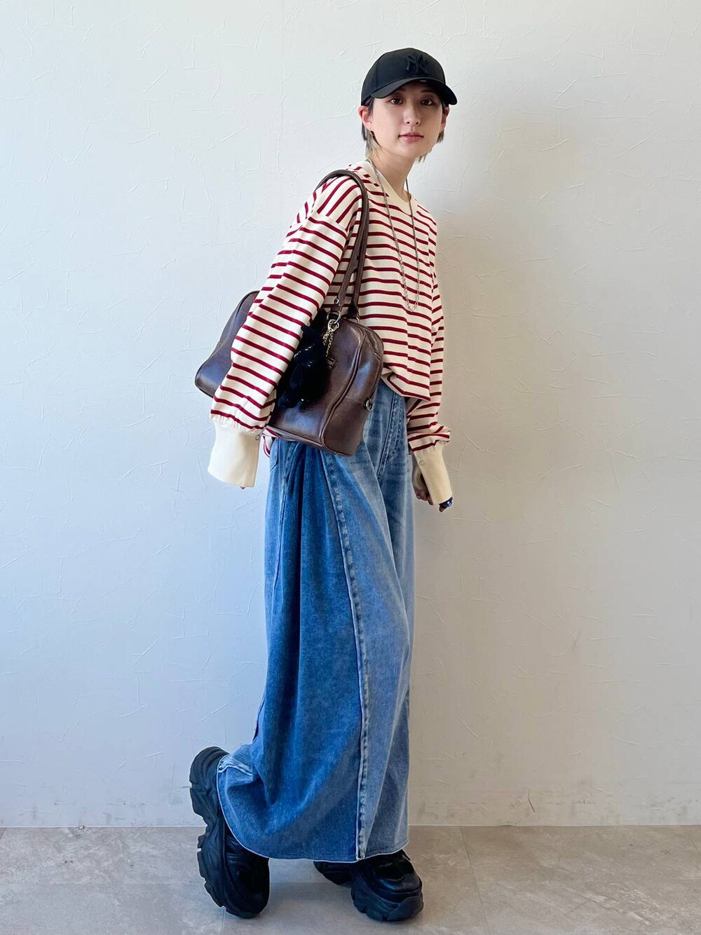 ブラック系のスニーカー、ブラウン系のボストンバッグ、ブルー系のデニムパンツを着用したレディースの春コーディネートの1枚目の写真