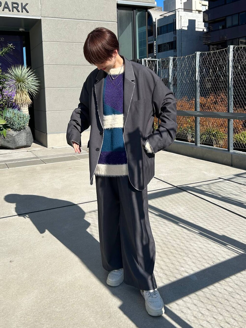 グレー系のスラックス、グレー系のテーラードジャケット、ブルー系のニット/セーターを着用したレディースの冬コーディネートの1枚目の写真