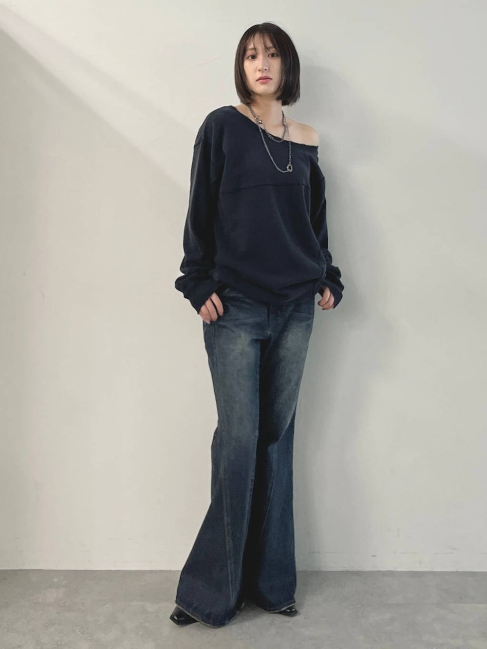 ブルー系のデニムパンツ、ブラック系のパンプス、グレー系のスウェットを着用したレディースの秋コーディネートの1枚目の写真