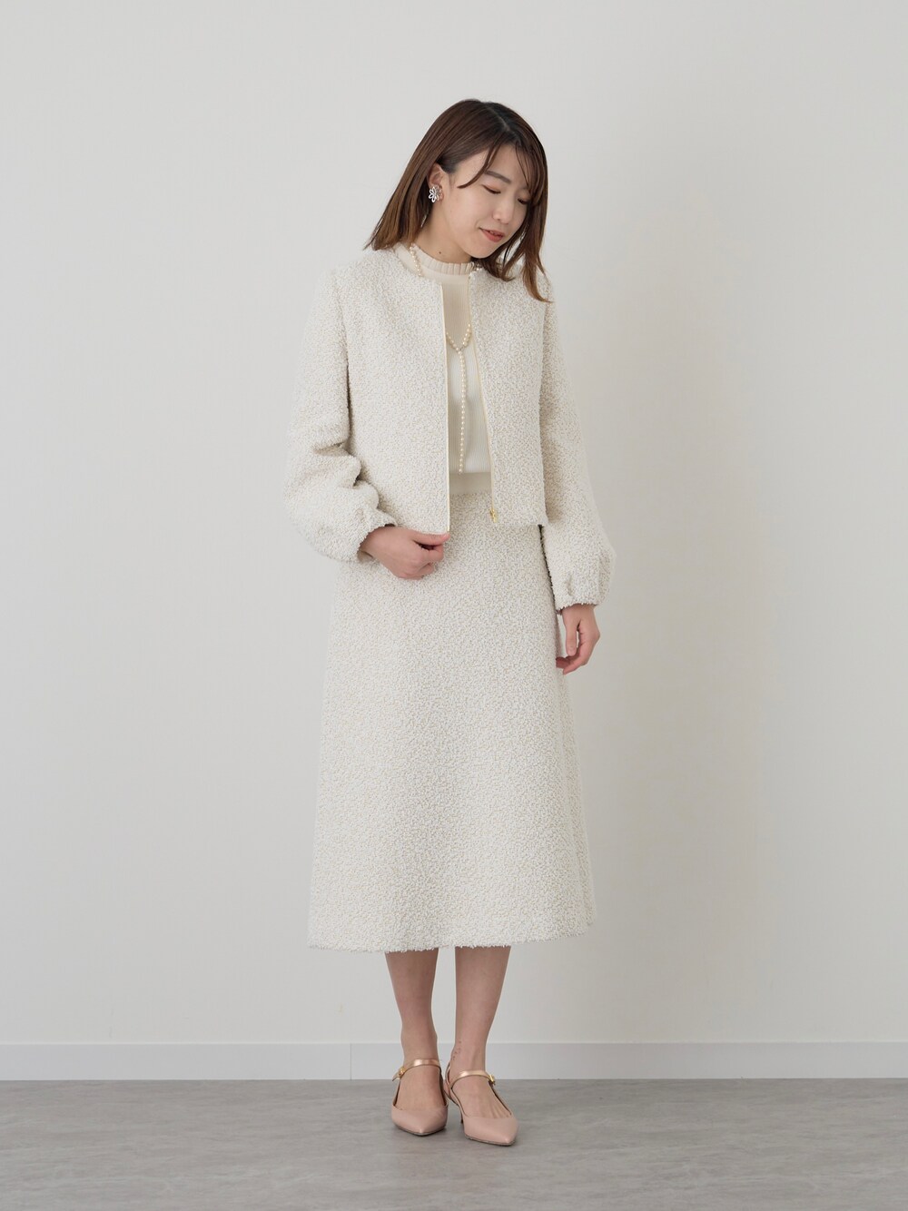 ホワイト系のノーカラージャケット、ホワイト系のスカートを着用したレディースの冬コーディネートの1枚目の写真