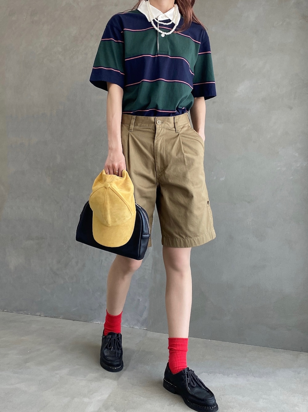 グリーン系のポロシャツ、ベージュ系のパンツ、ブラック系のドレスシューズを着用したレディースの春コーディネートの1枚目の写真