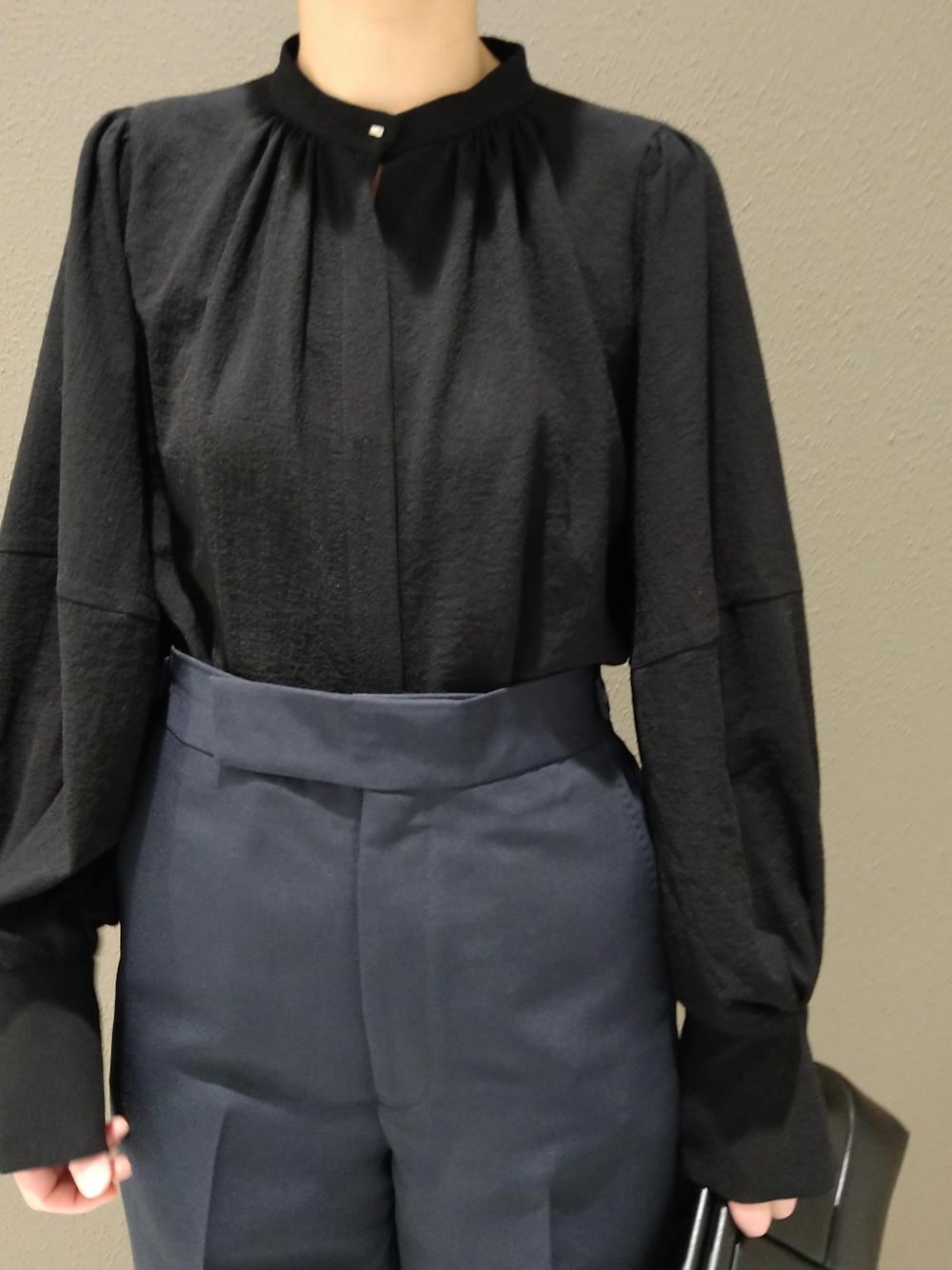 ブラック系のシャツ/ブラウス、ブルー系のスラックス、ブラック系のクラッチバッグを着用したレディースの冬コーディネートの2枚目の写真