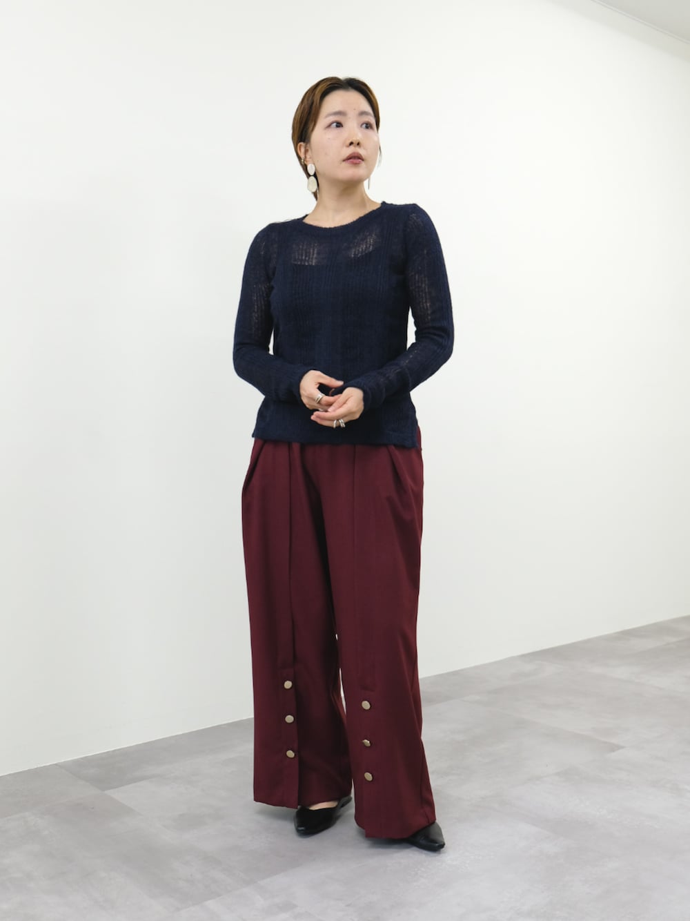 ブルー系のニット/セーター、レッド系のスラックスを着用したレディースの秋コーディネートの1枚目の写真