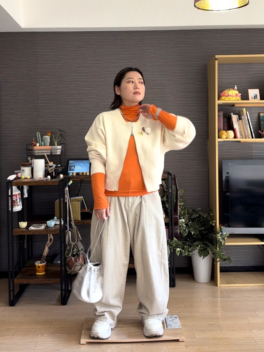 ホワイト系のパンツ、ホワイト系のカーディガン/ボレロ、オレンジ系のTシャツ/カットソーを着用したレディースの春コーディネートの1枚目の写真