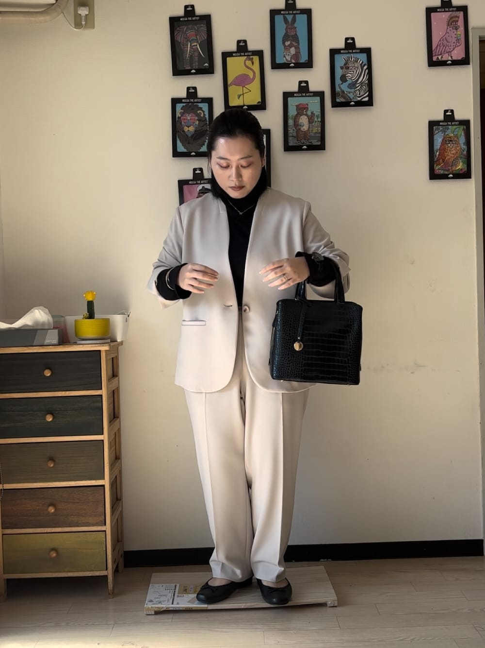 ベージュ系のスーツジャケット、ベージュ系のスーツパンツ、ブラック系のバッグを着用したレディースの冬コーディネートの1枚目の写真