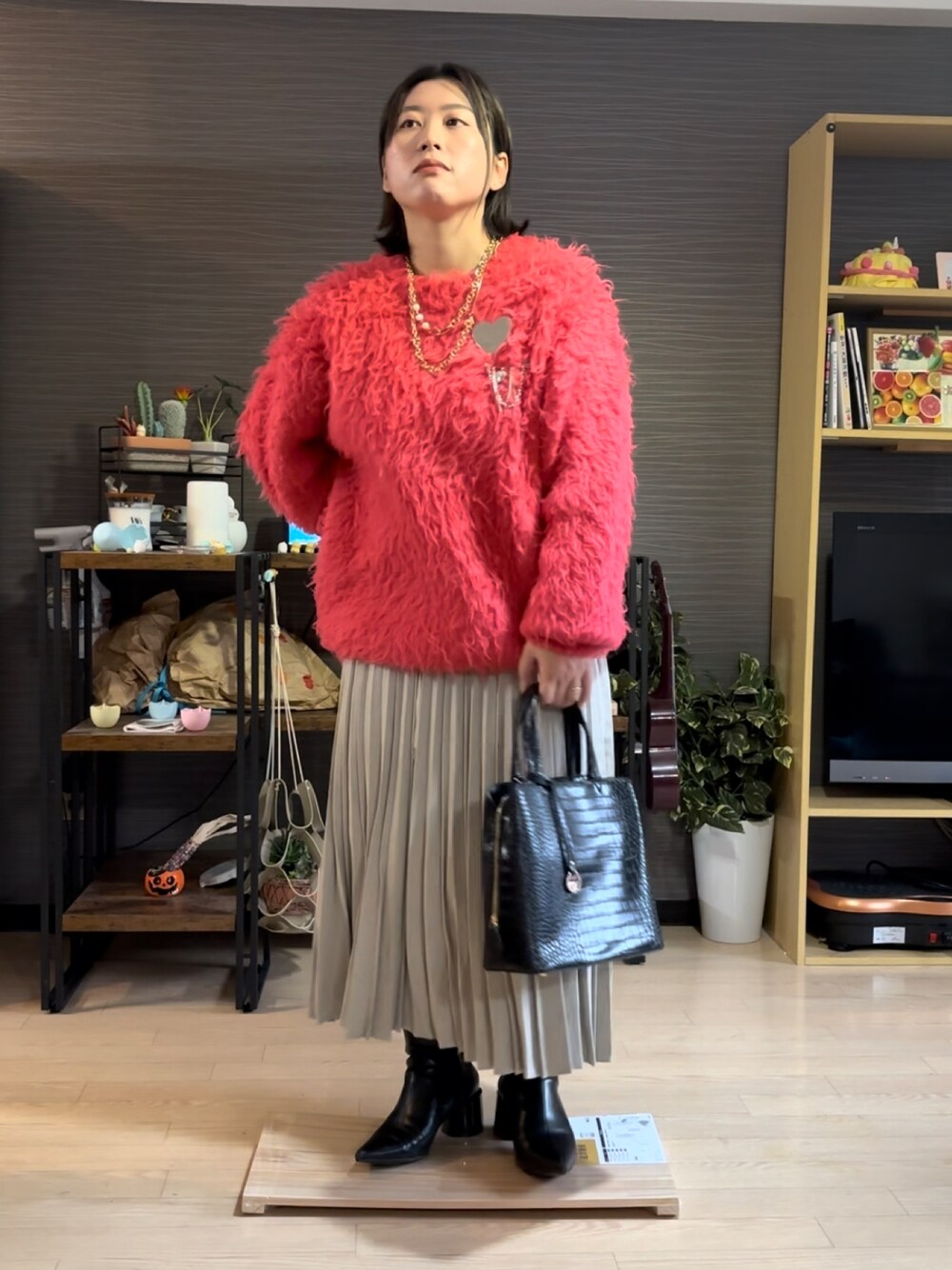 ピンク系のニット/セーター、ブラック系のバッグ、ブラック系のブーツを着用したレディースの冬コーディネートの1枚目の写真
