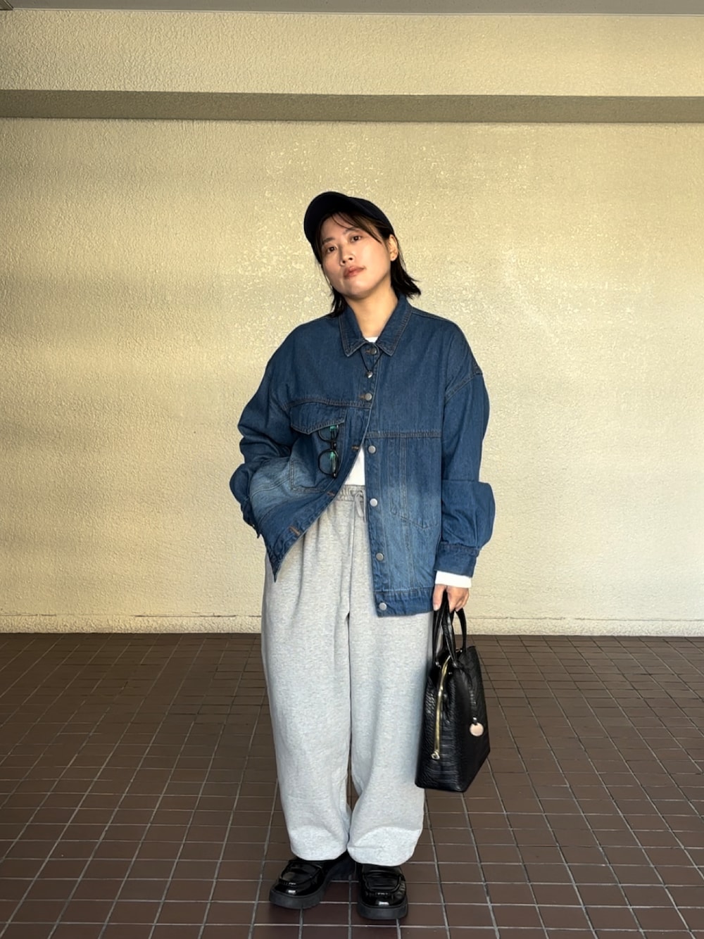 ホワイト系のスウェットパンツ、ブルー系のデニムジャケット、ブラック系のバッグを着用したレディースの冬コーディネートの1枚目の写真