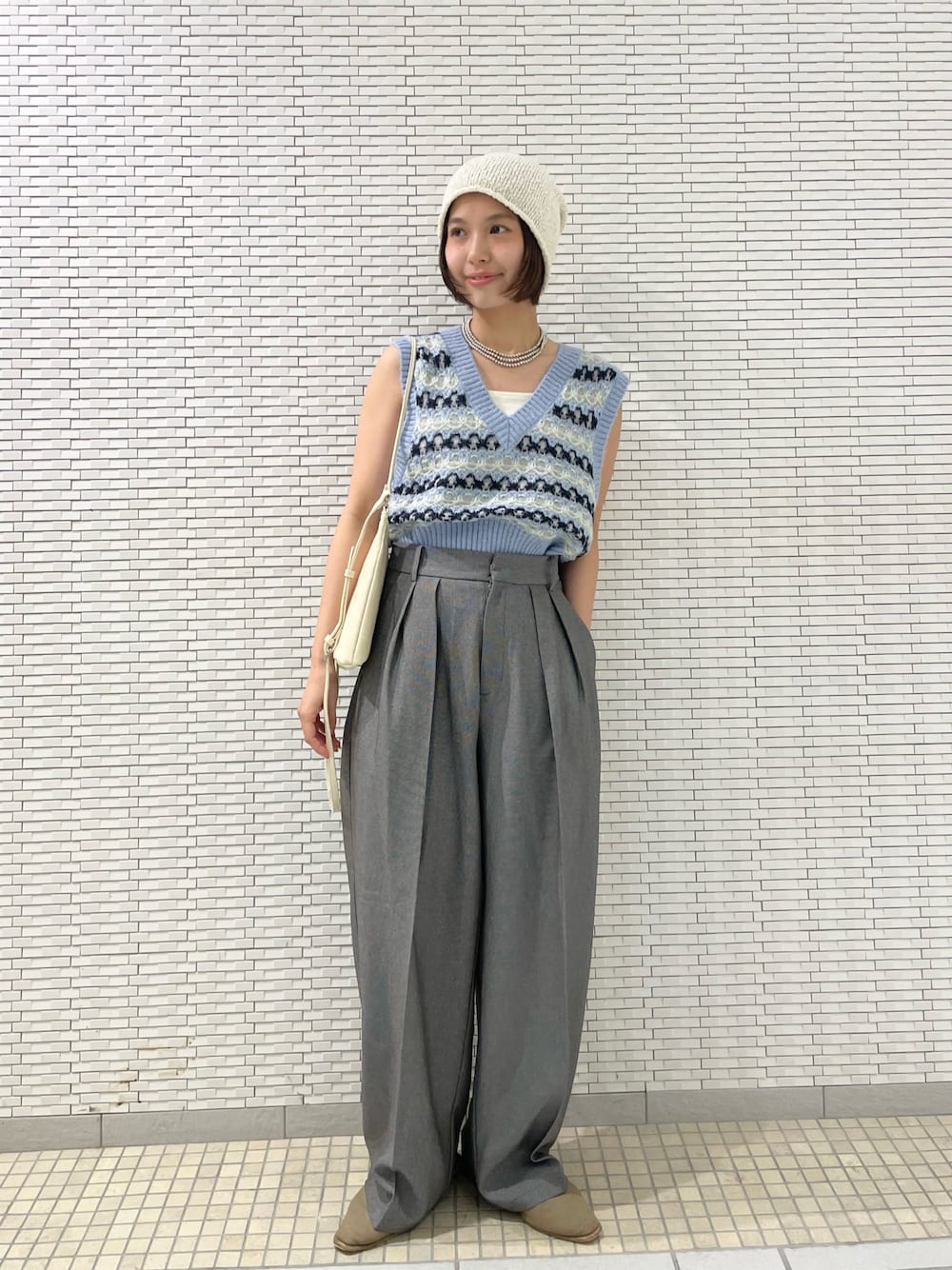 グレー系のその他パンツ、ブルー系のベスト、ホワイト系のショルダーバッグを着用したレディースの夏コーディネートの1枚目の写真