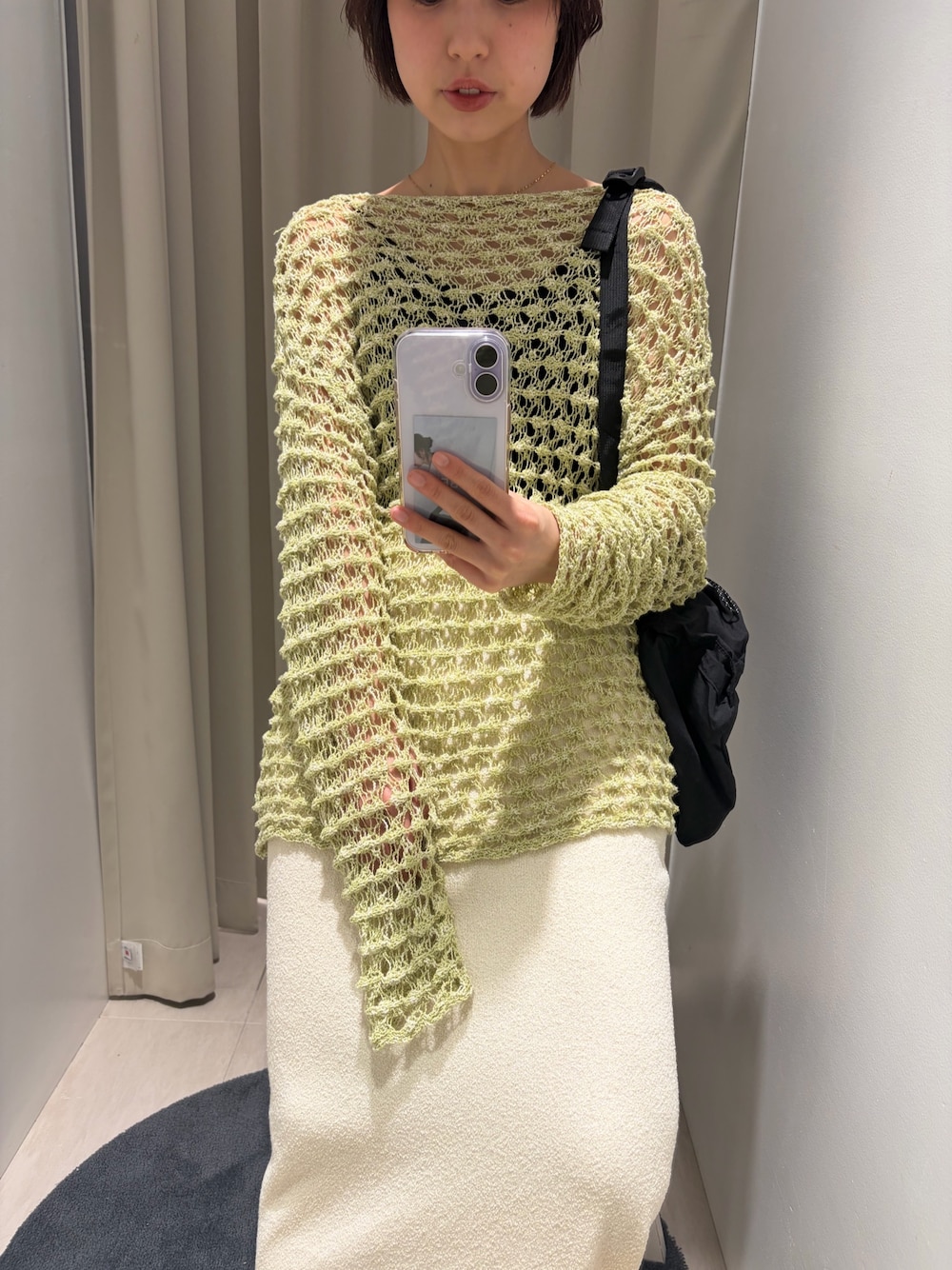 グリーン系のニット/セーター、ホワイト系のスカート、ブラック系のバックパック/リュックを着用したレディースの春コーディネートの1枚目の写真