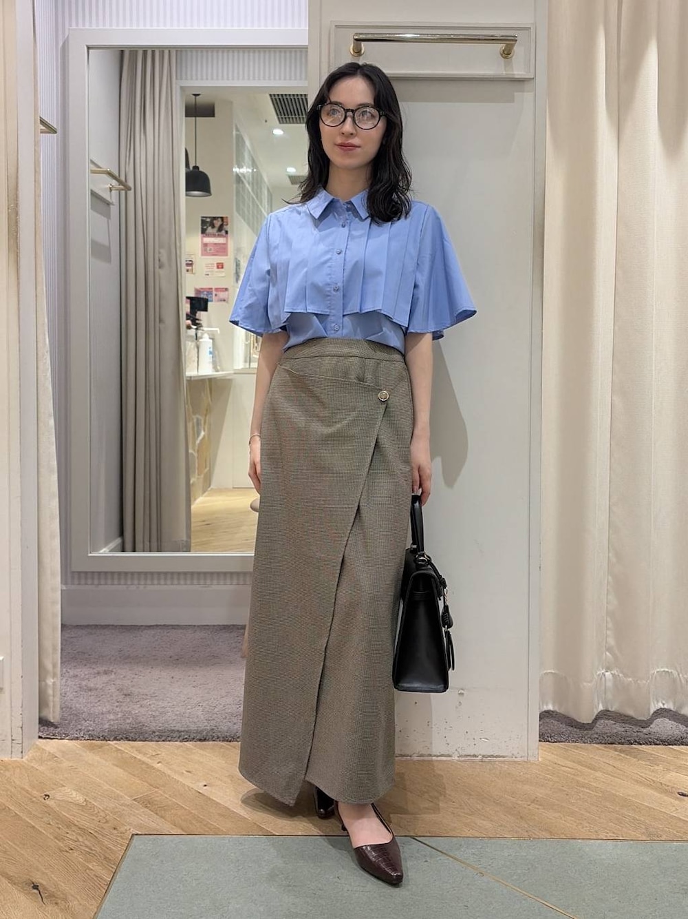 ベージュ系のスカート、ブルー系のシャツ/ブラウス、ブラウン系のパンプスを着用したレディースの夏コーディネートの1枚目の写真