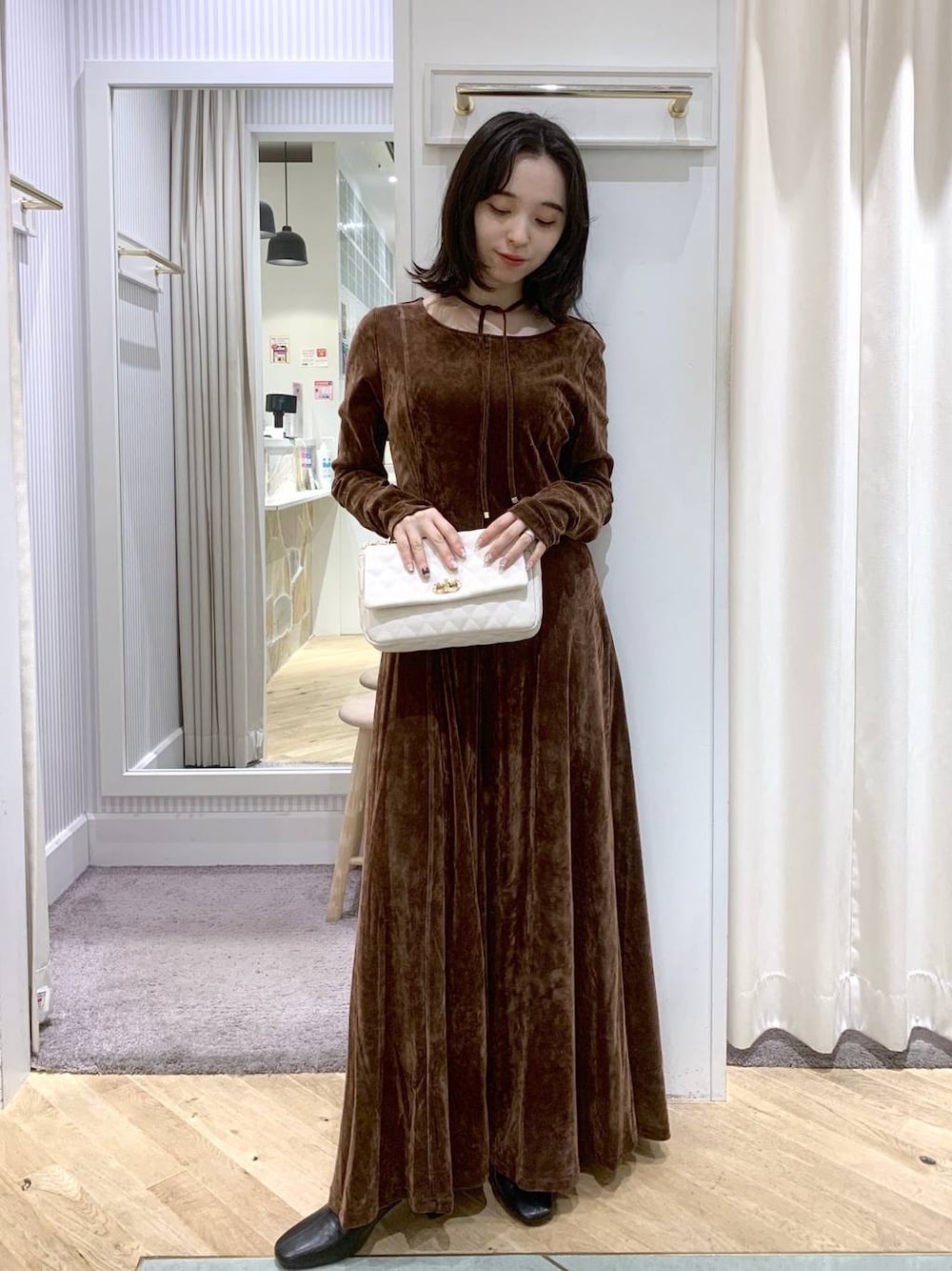 ブラック系のブーツ、ホワイト系のショルダーバッグ、ブラウン系のワンピースを着用したレディースの秋コーディネートの1枚目の写真