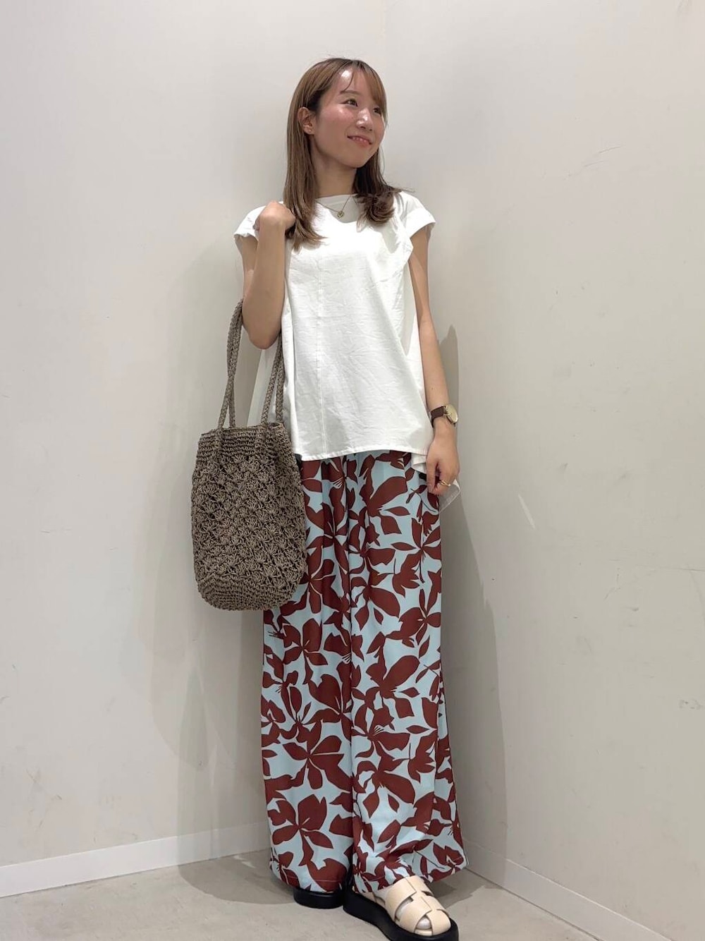 グレー系のトートバッグ、ホワイト系のサンダル、ホワイト系のTシャツ/カットソーを着用したレディースの春コーディネートの1枚目の写真