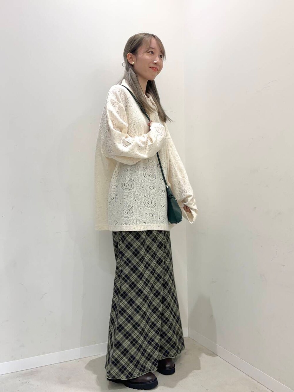 グリーン系のショルダーバッグ、ブラウン系のブーツ、グリーン系のスカートを着用したレディースの秋コーディネートの1枚目の写真