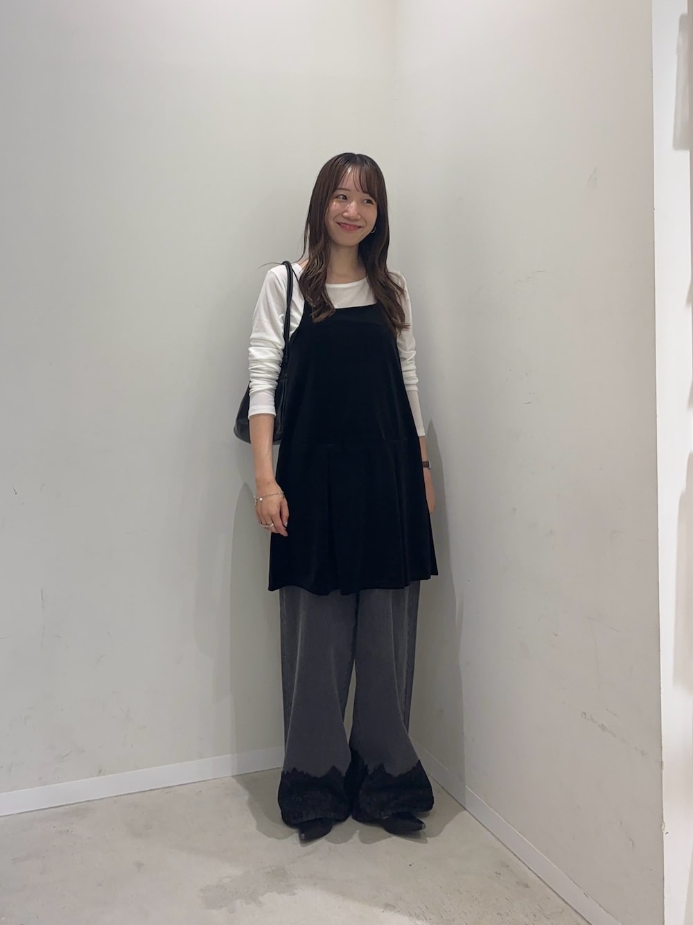ブラック系のチュニック、ホワイト系のTシャツ/カットソー、グレー系のデニムパンツを着用したレディースの秋コーディネートの1枚目の写真