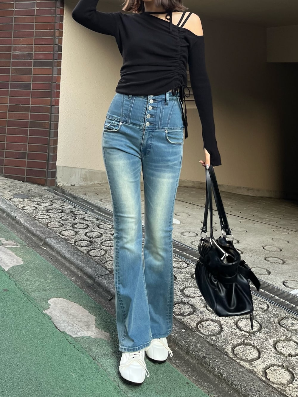 ブラック系のトートバッグ、ブラック系のニット/セーター、ブルー系のデニムパンツを着用したレディースの冬コーディネートの1枚目の写真