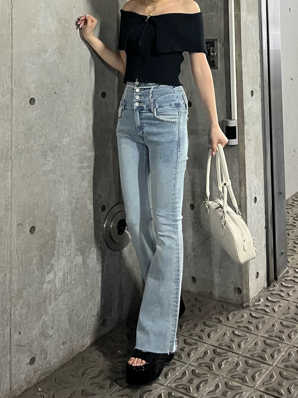 ブラック系のニット/セーター、ブルー系のデニムパンツ、ブラック系のサンダルを着用したレディースの春コーディネートの1枚目の写真
