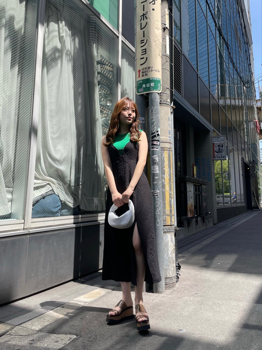 ホワイト系のハンドバッグ、ブラック系のサンダル、グリーン系のタンクトップを着用したレディースの春コーディネートの1枚目の写真