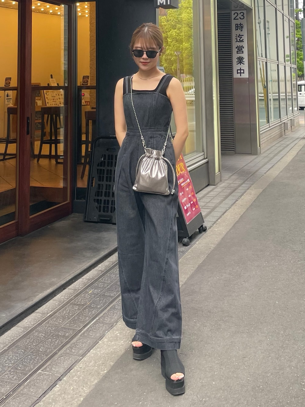 グレー系のショルダーバッグ、ブラック系のブーツ、ブラック系のニット/セーターを着用したレディースの春コーディネートの1枚目の写真