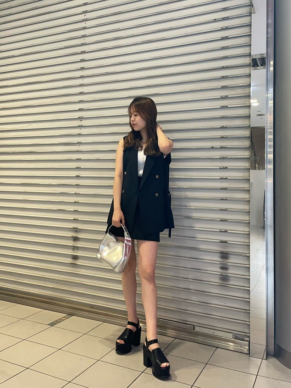 ブラック系のスカート、ホワイト系のタンクトップ、シルバー系のハンドバッグを着用したレディースの夏コーディネートの1枚目の写真