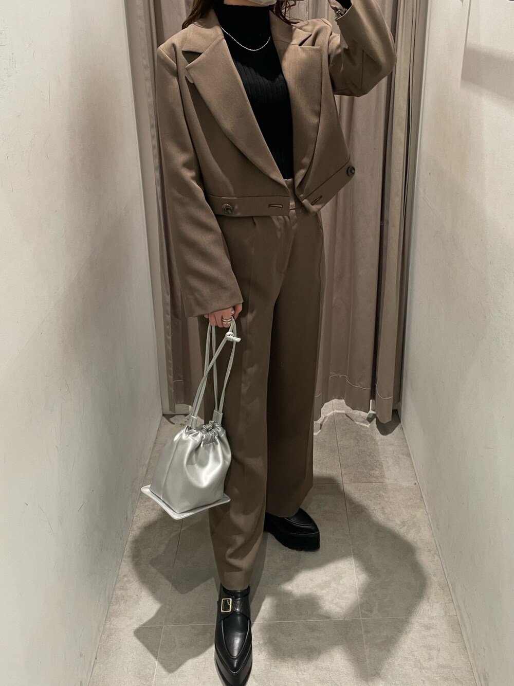ブラウン系のテーラードジャケット、ブラック系のニット/セーター、シルバー系のハンドバッグを着用したレディースの春コーディネートの1枚目の写真