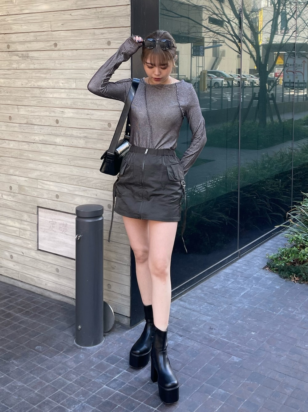 ブラック系のショルダーバッグ、グレー系のTシャツ/カットソー、ベージュ系のスカートを着用したレディースの冬コーディネートの1枚目の写真