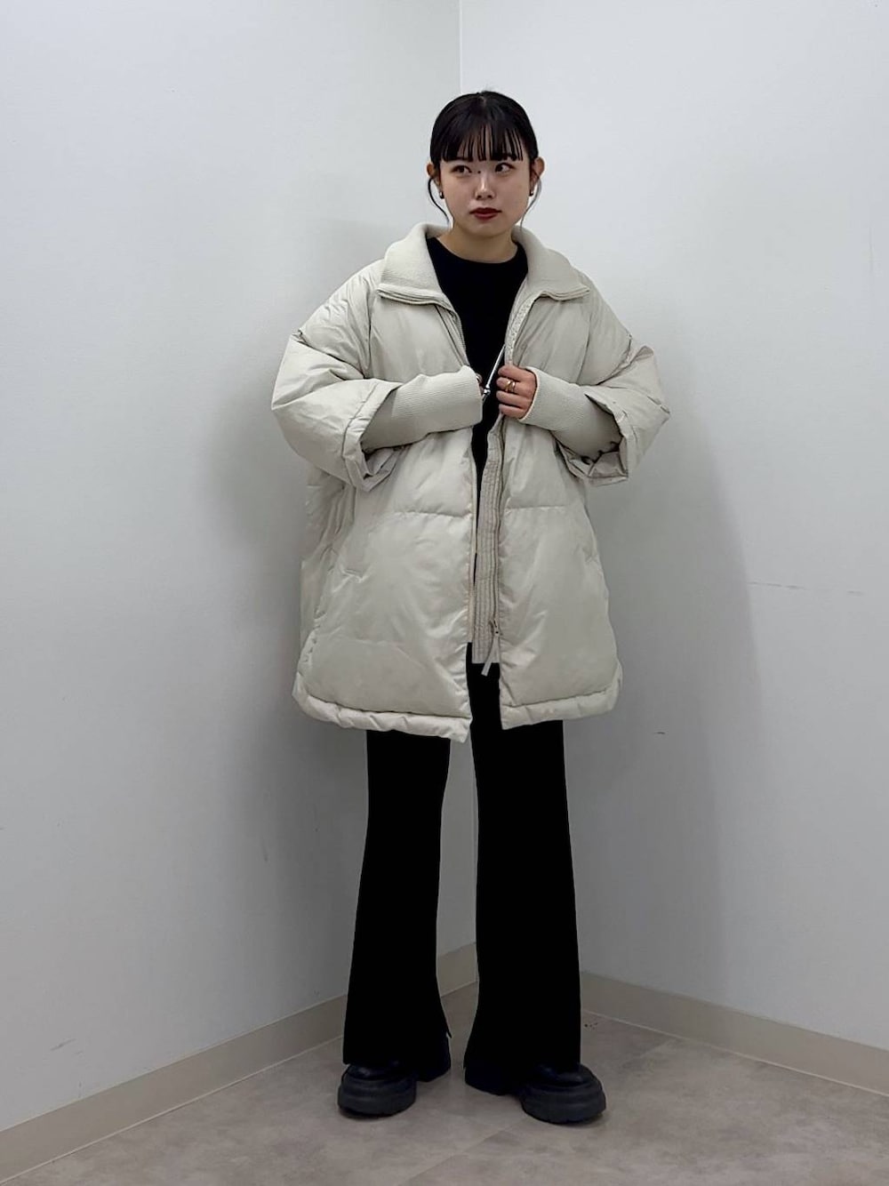 シルバー系のショルダーバッグ、ホワイト系のポンチョ、ブラック系のTシャツ/カットソーを着用したレディースの秋コーディネートの1枚目の写真
